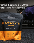 Black and orange pouch of Just Ingredients Performance Electrolytes in orange flavor with sodium and potassium content displa