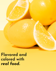 A stack of whole lemons and lemon slices on a yellow background with text about real food flavoring.