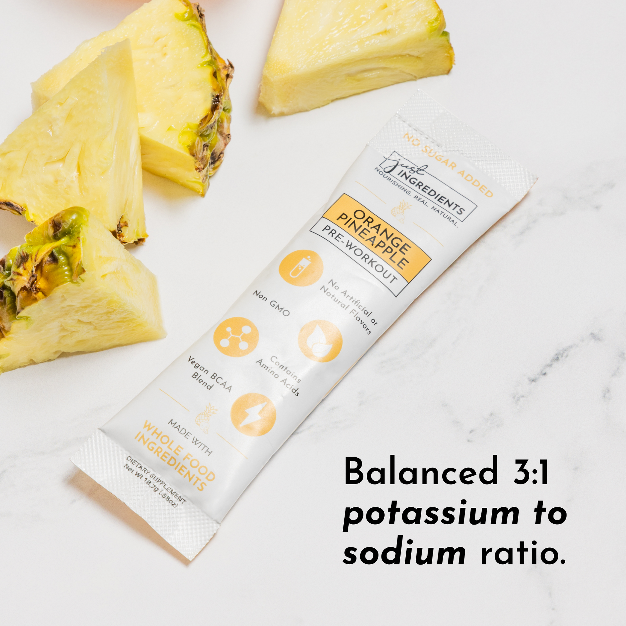 Stick packet labeled "Orange Pineapple Pre-Workout" beside fresh pineapple slices on a marble surface.