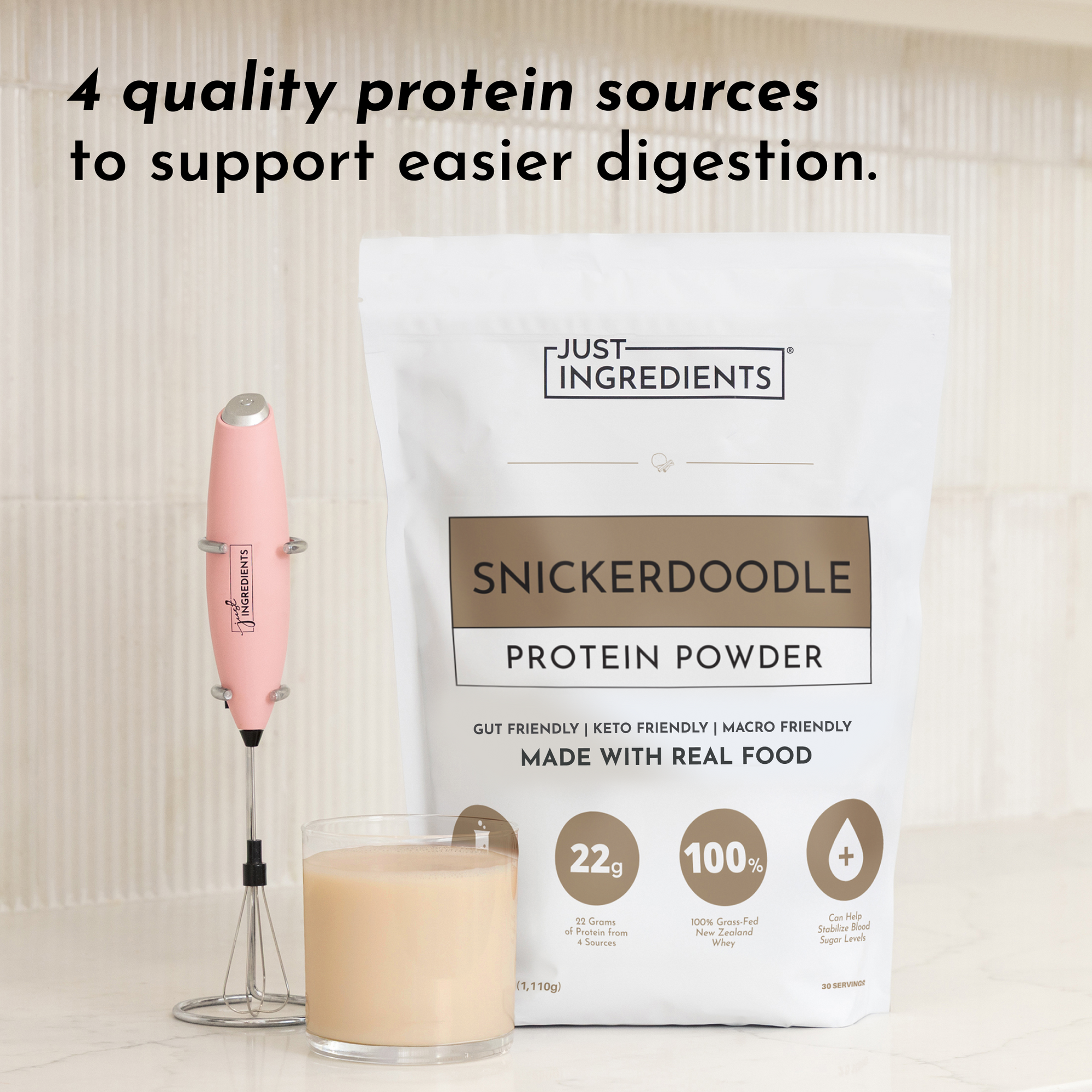 White pouch of Snickerdoodle Protein Powder with pink milk frother and glass of tan-colored beverage.