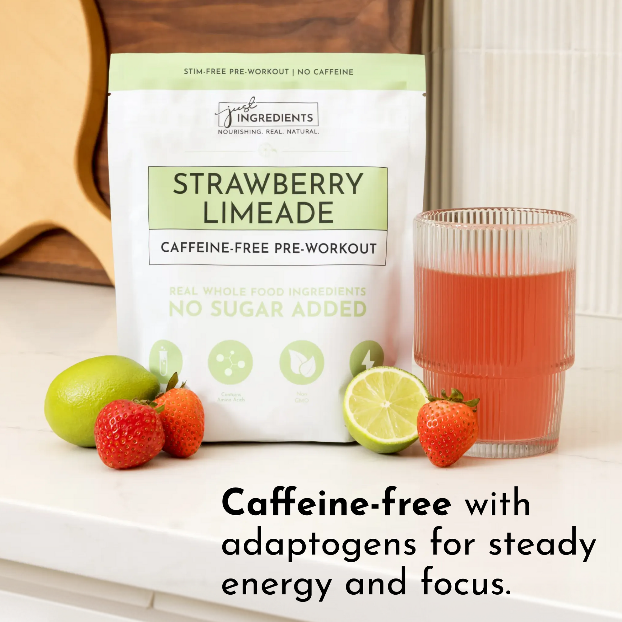 Caffeine-free pre-workout powder package next to a glass of strawberry limeade and fresh strawberries and lime.