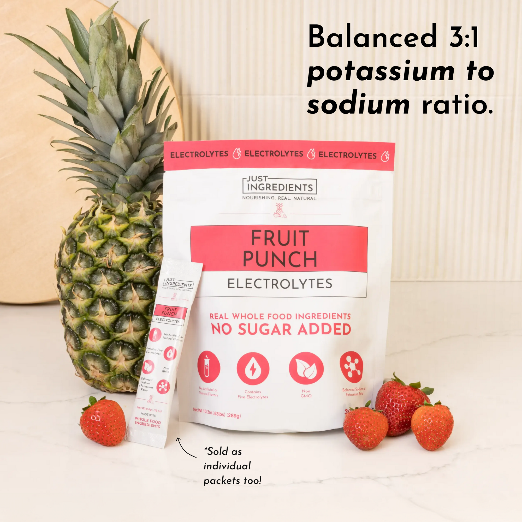 Fruit Punch Electrolytes package with a pineapple and strawberries on a marble surface.