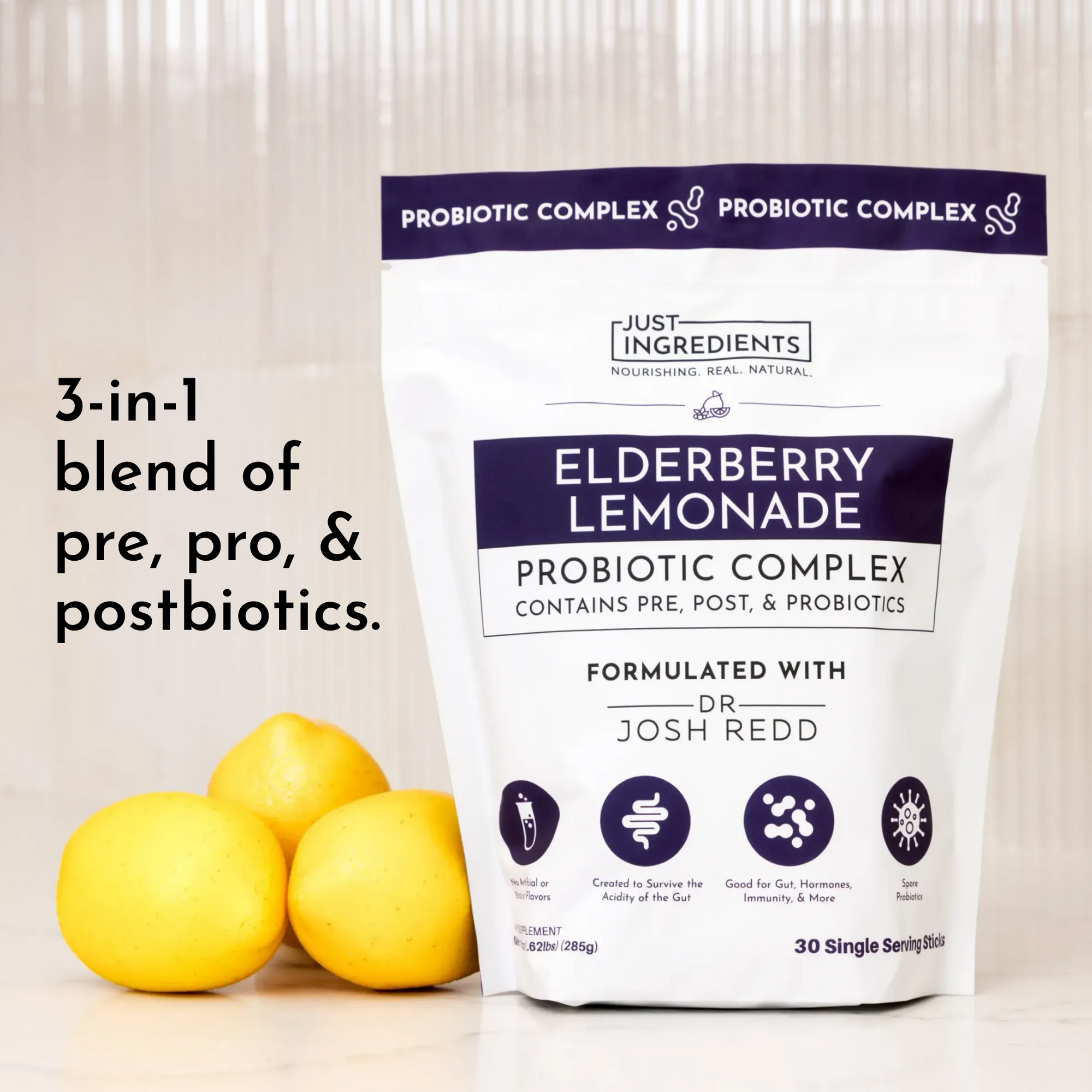 White pouch labeled "Elderberry Lemonade Probiotic Complex" with three lemons in front, featuring nutritional information.