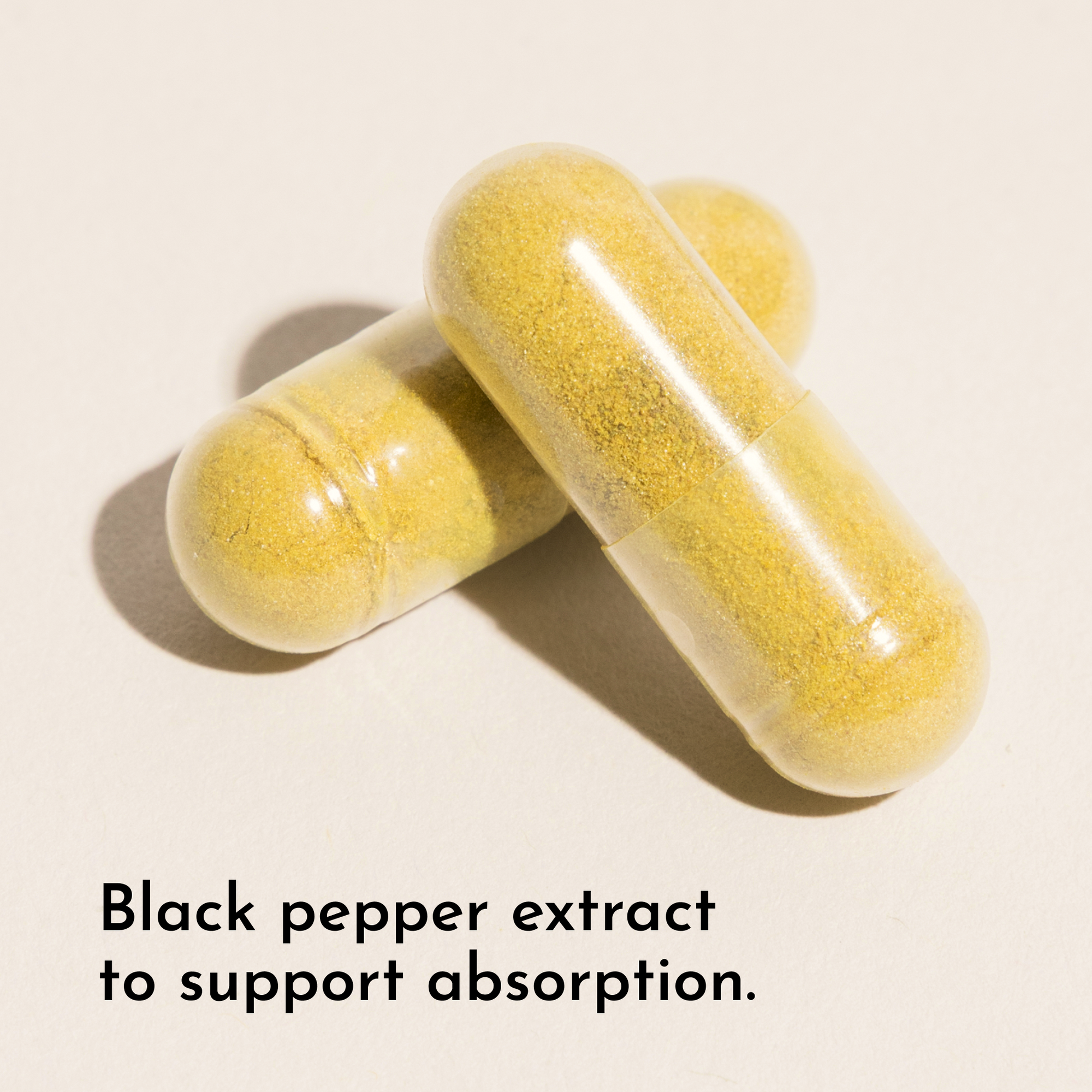 Three yellow capsules filled with fine powder on a beige background.