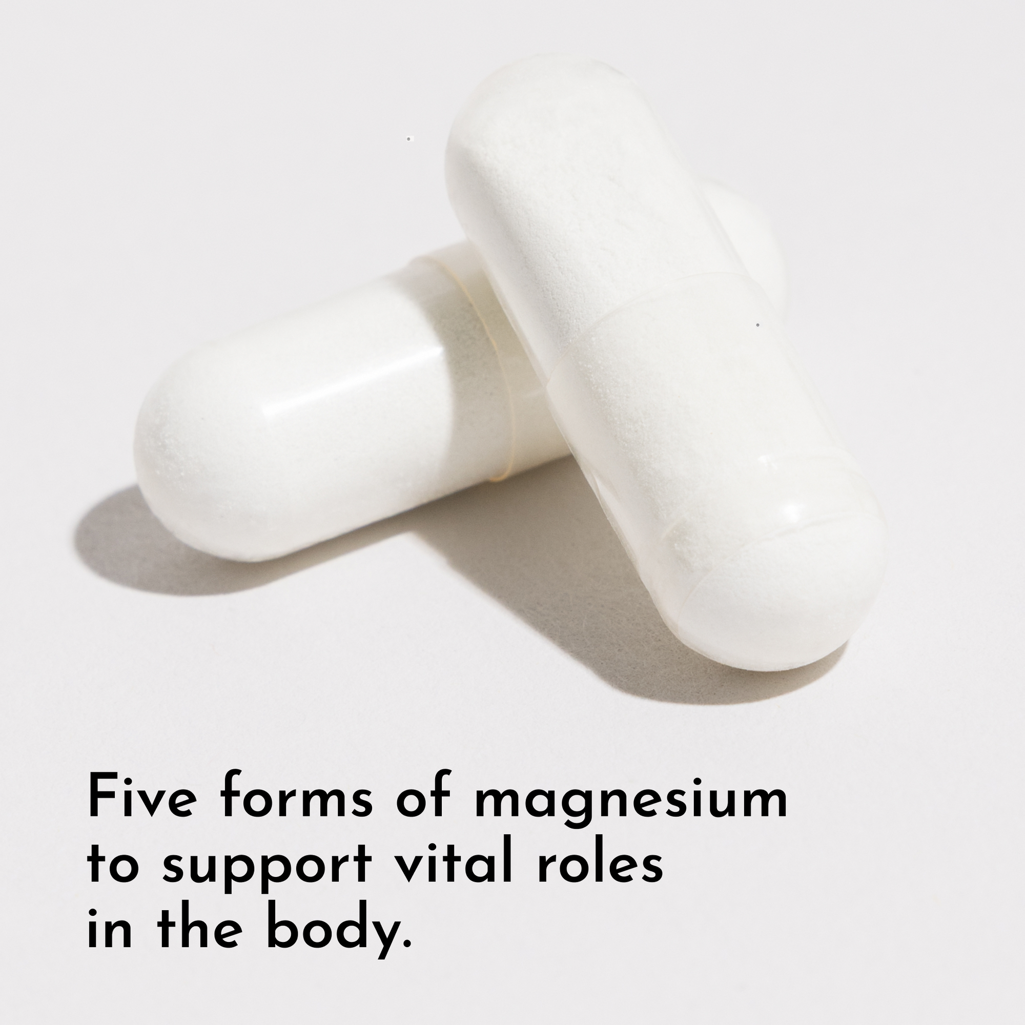 Two white capsule pills on a light gray background.