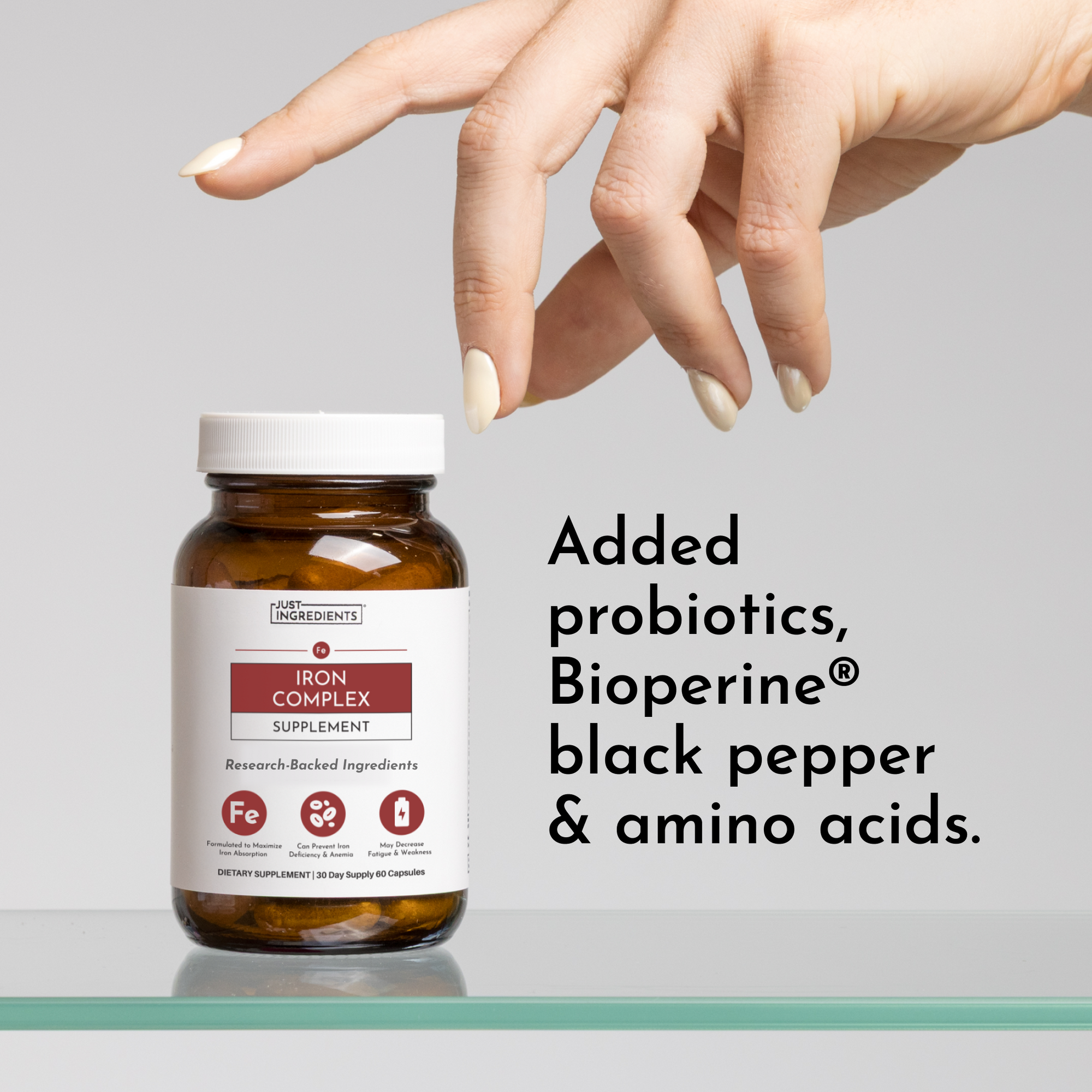 Brown glass bottle of Iron Complex supplement with white cap, hand hovering above, label visible on gray background.