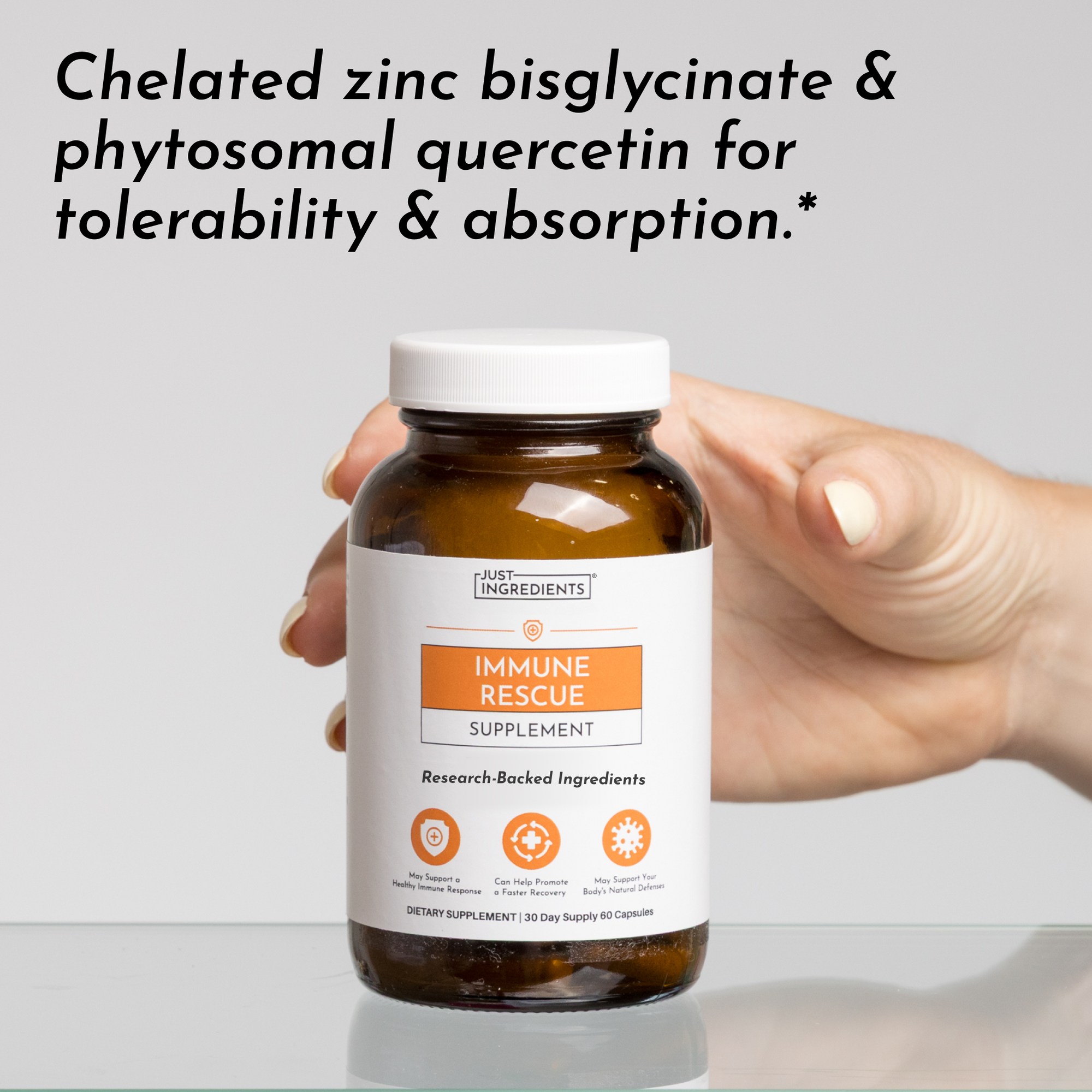 Hand holding amber glass bottle of Immune Rescue supplement with white cap and orange label.