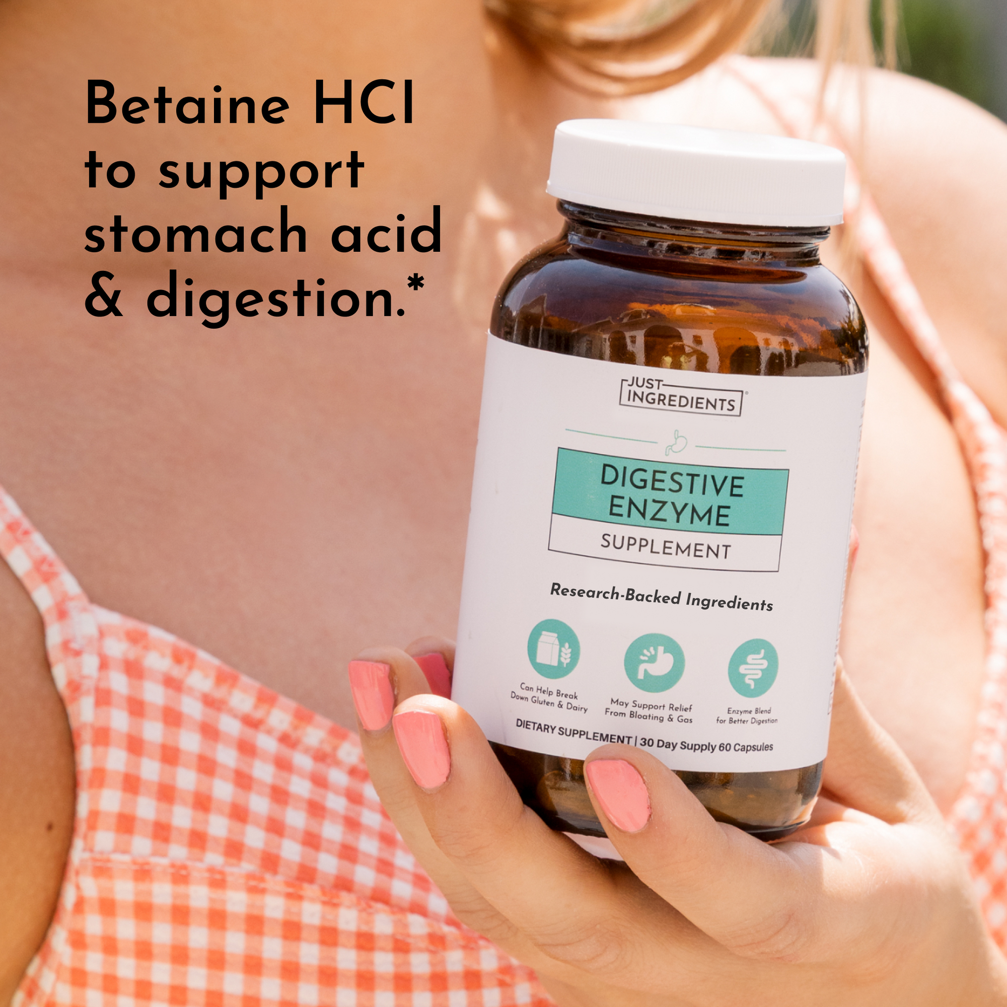 Brown glass bottle of digestive enzyme supplement with white label held in hand with pink nail polish.