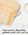 Packaging of toasted vanilla bone broth protein powder with a cup of blended powder and a vanilla bean.