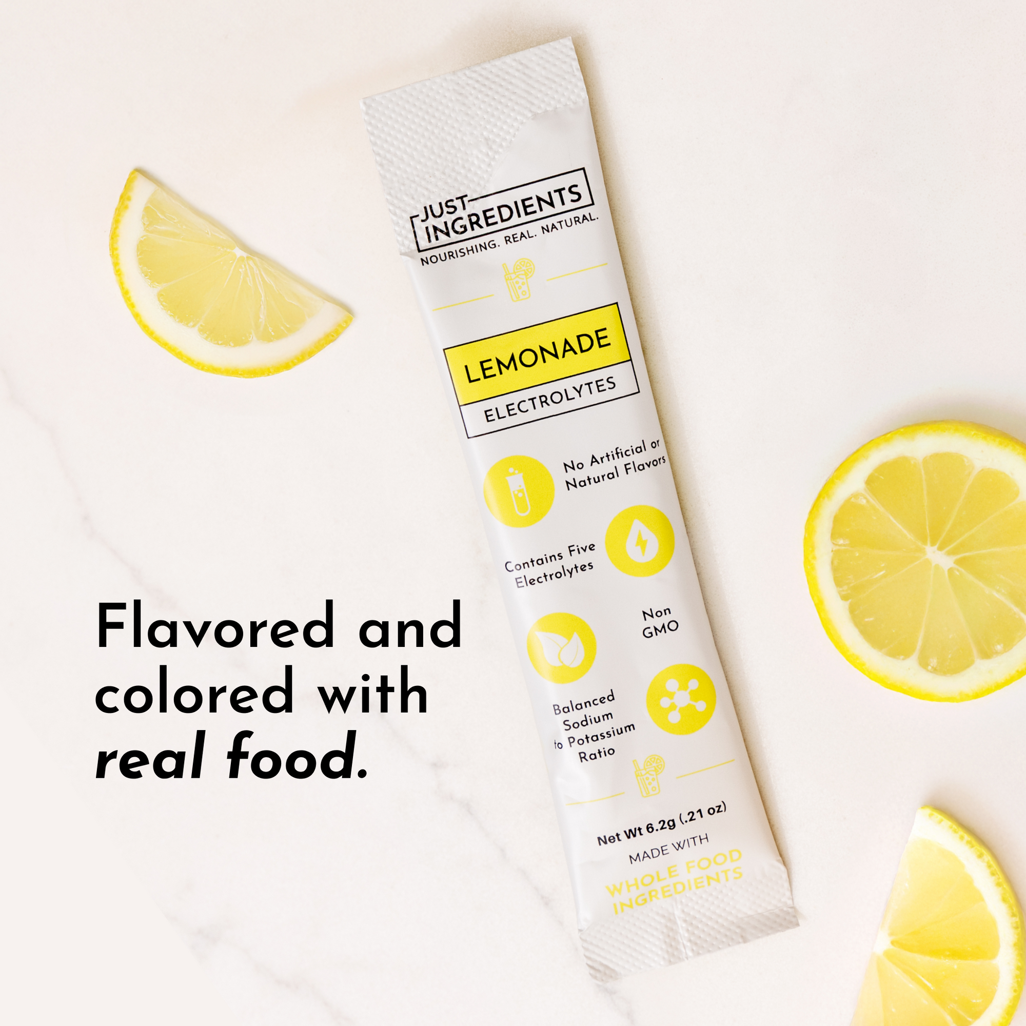Lemonade electrolytes stick next to lemon slices on a marble surface, featuring product information on the packaging.
