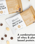 Two protein snack bars in packaging, with chocolate chips and peanuts scattered around.