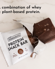 Chocolate protein snack bar partially unwrapped, showing a rich chocolate color and packaging details.