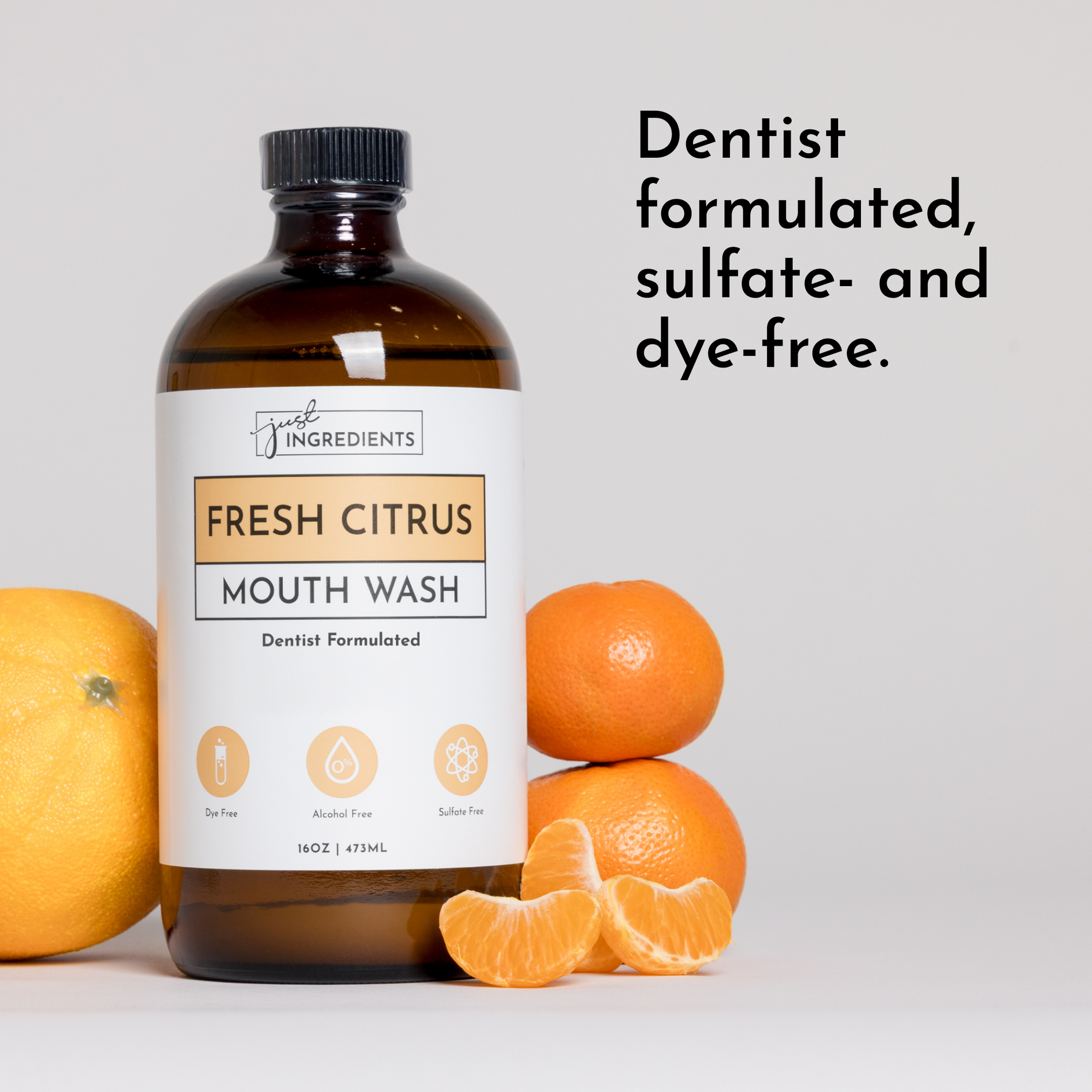 Brown glass bottle of Fresh Citrus mouth wash with citrus fruits beside it, labeled as dentist formulated and free from sulfa