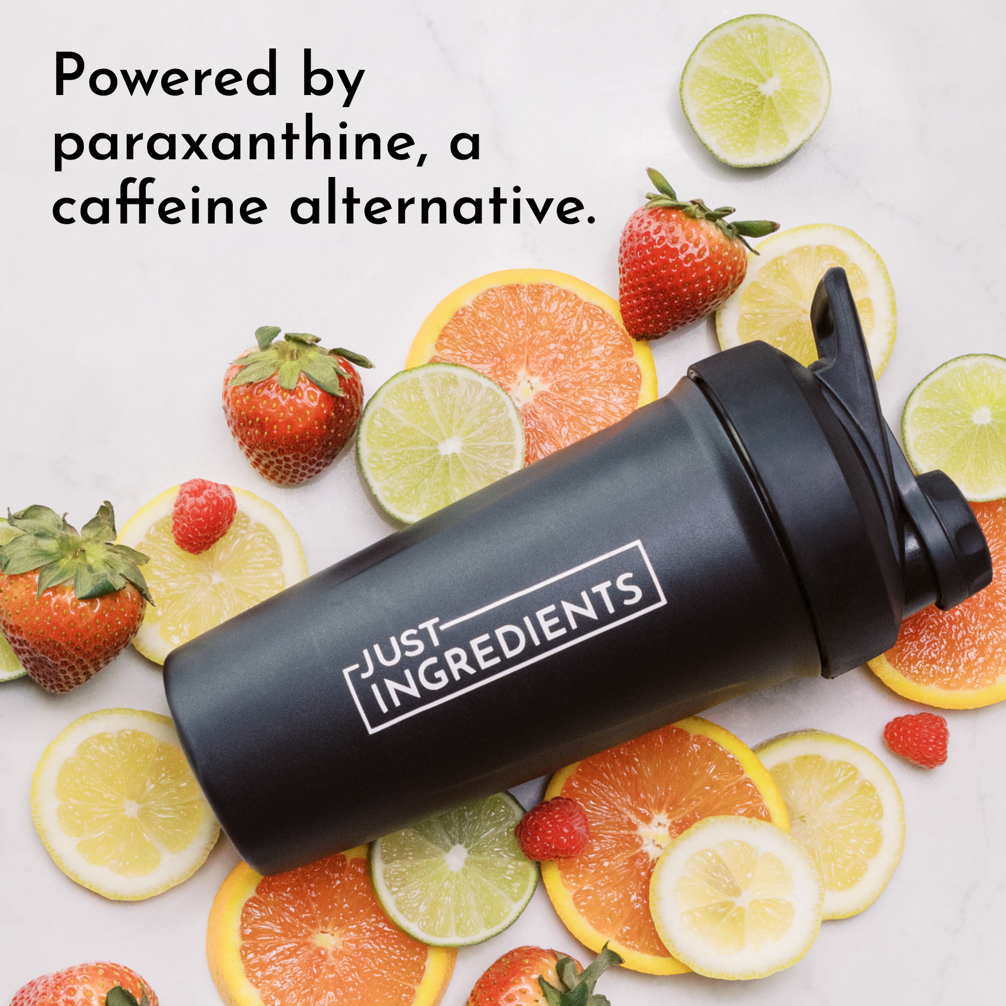 Black shaker bottle with "Just Ingredients" label surrounded by fresh strawberries, oranges, lemons, and limes.