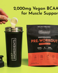 Black shaker bottle with powder being poured in and black/orange pouch of watermelon lime pre-workout powder on yellow backgr
