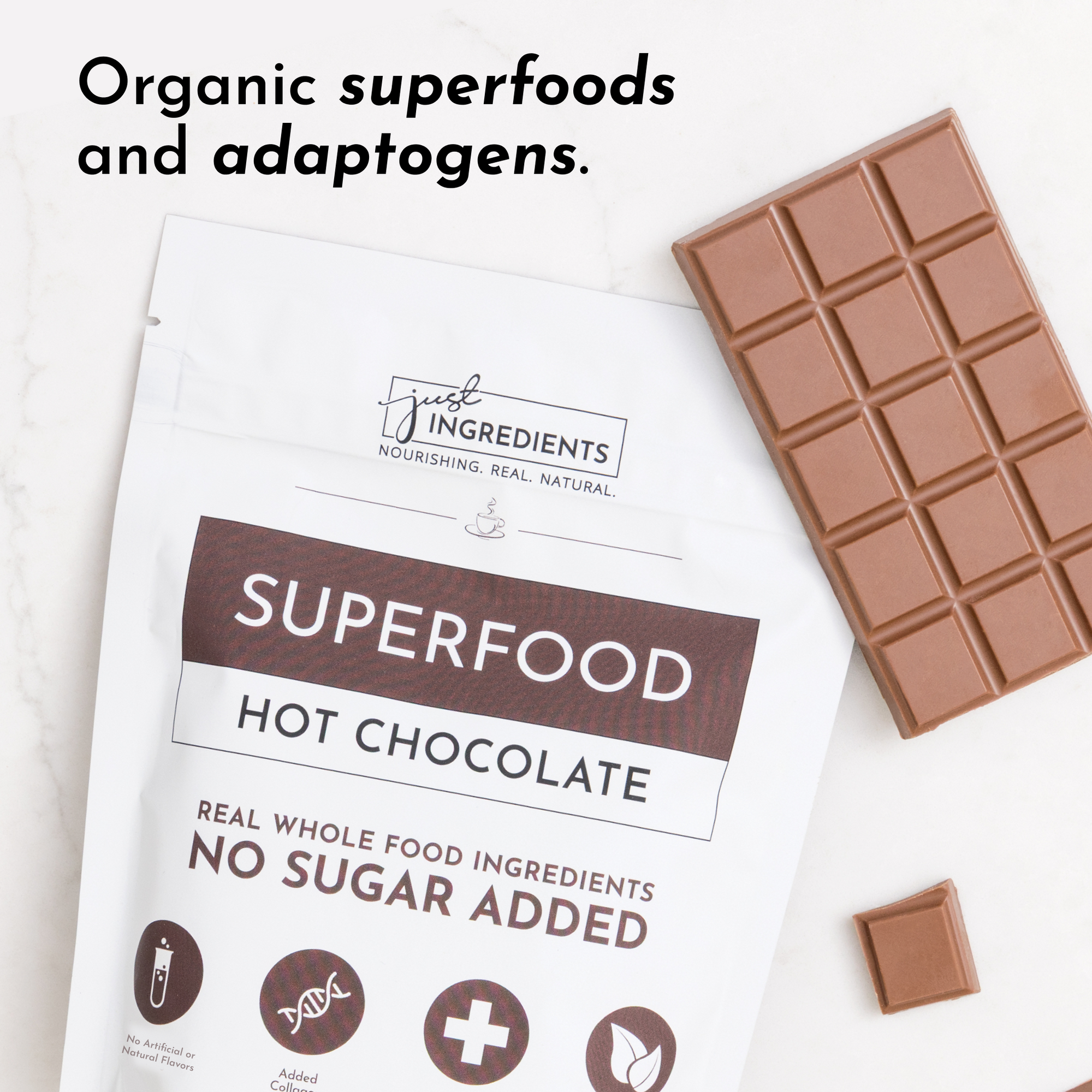 Pouch of Superfood Hot Chocolate next to a chocolate bar and a square piece on a marble surface.
