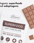 Pouch of Superfood Hot Chocolate next to a chocolate bar and a square piece on a marble surface.