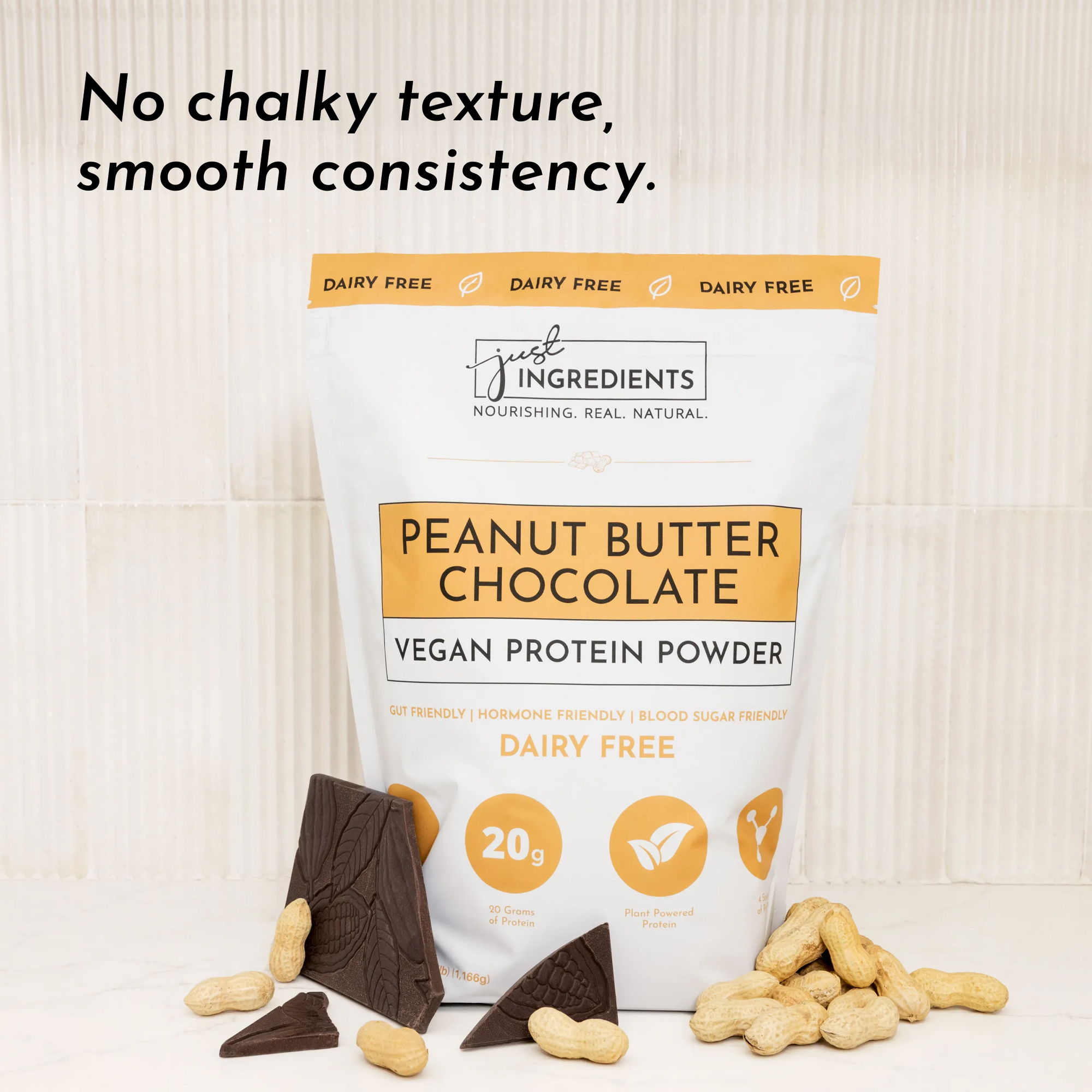 White bag of vegan peanut butter chocolate protein powder with chocolate pieces and peanuts on a light surface.