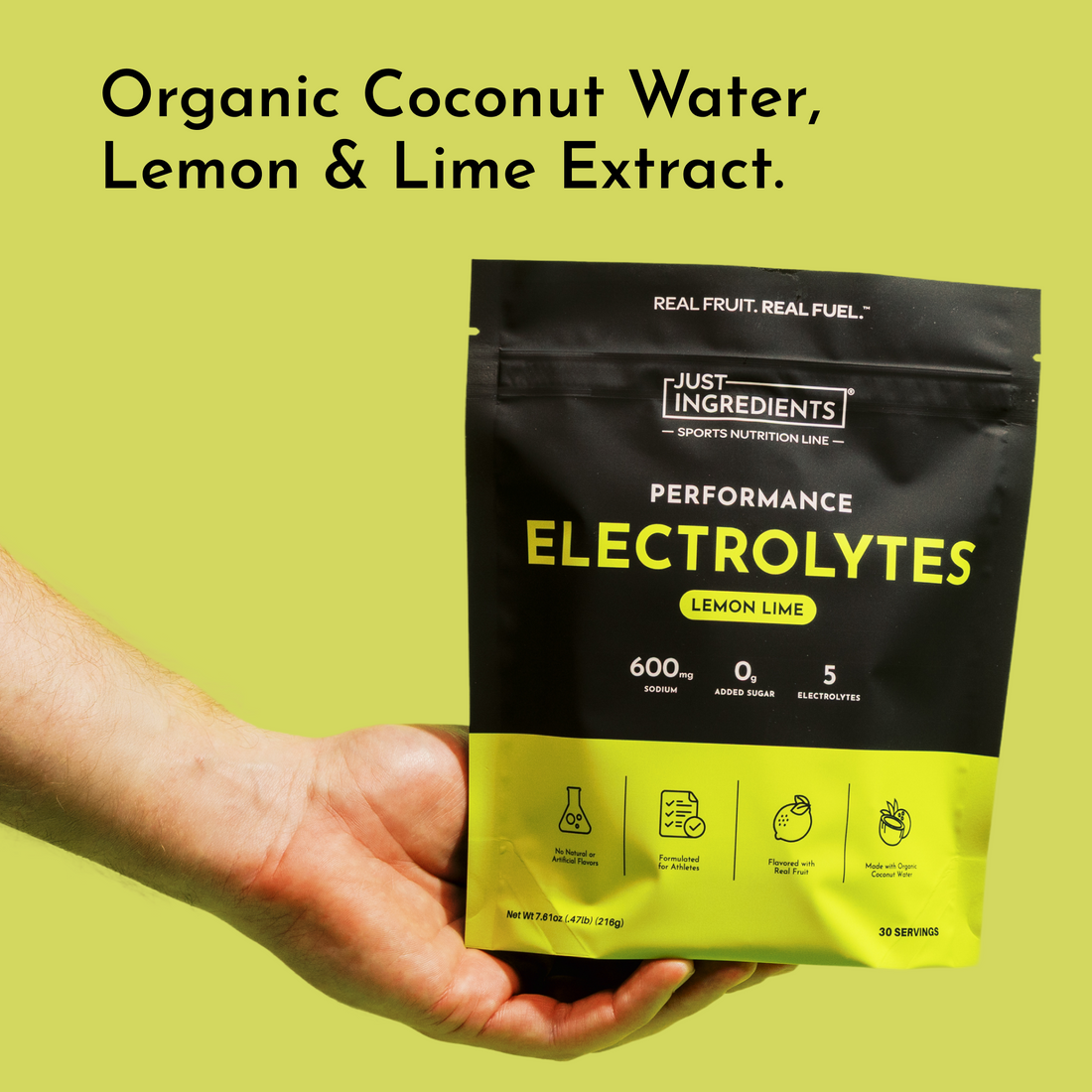 Hand holding a lemon lime electrolyte pouch against a yellow background.