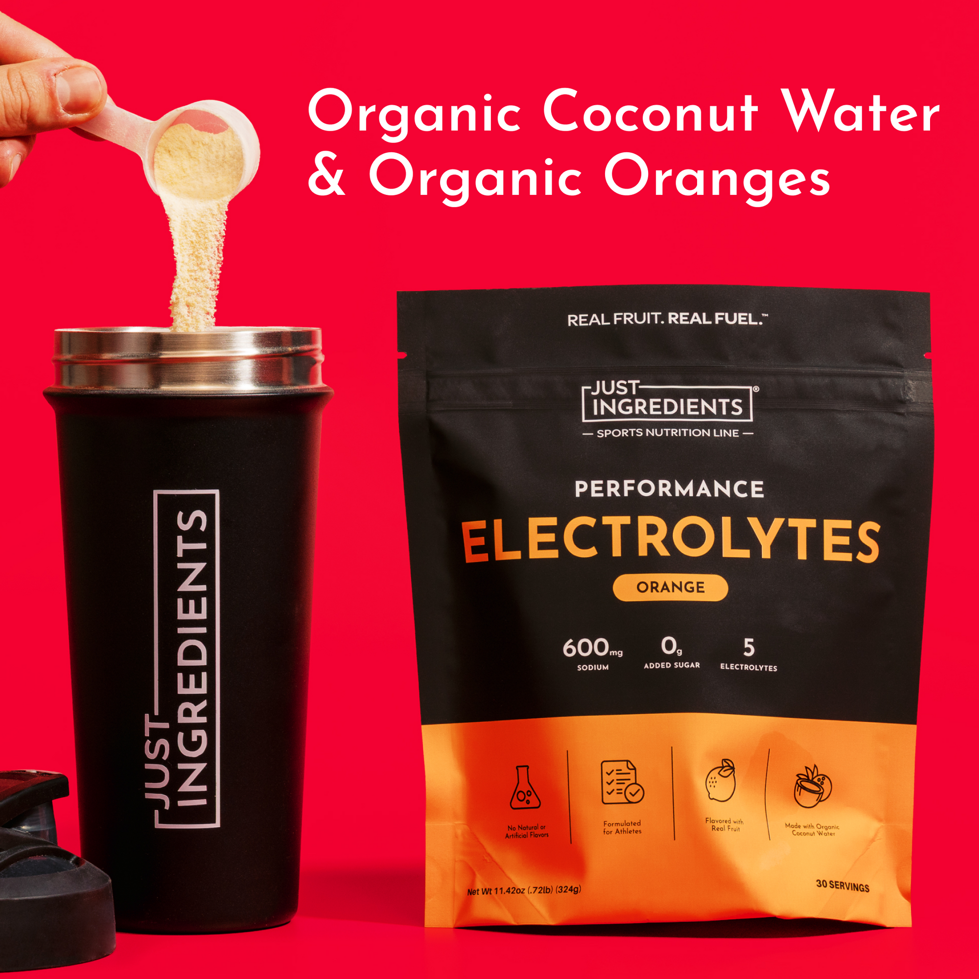 Powder being poured from a spoon into a black tumbler next to a black pouch of orange electrolyte powder on red background.