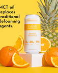 Clear protein drink can with orange and pineapple, surrounded by fresh oranges on a yellow background.