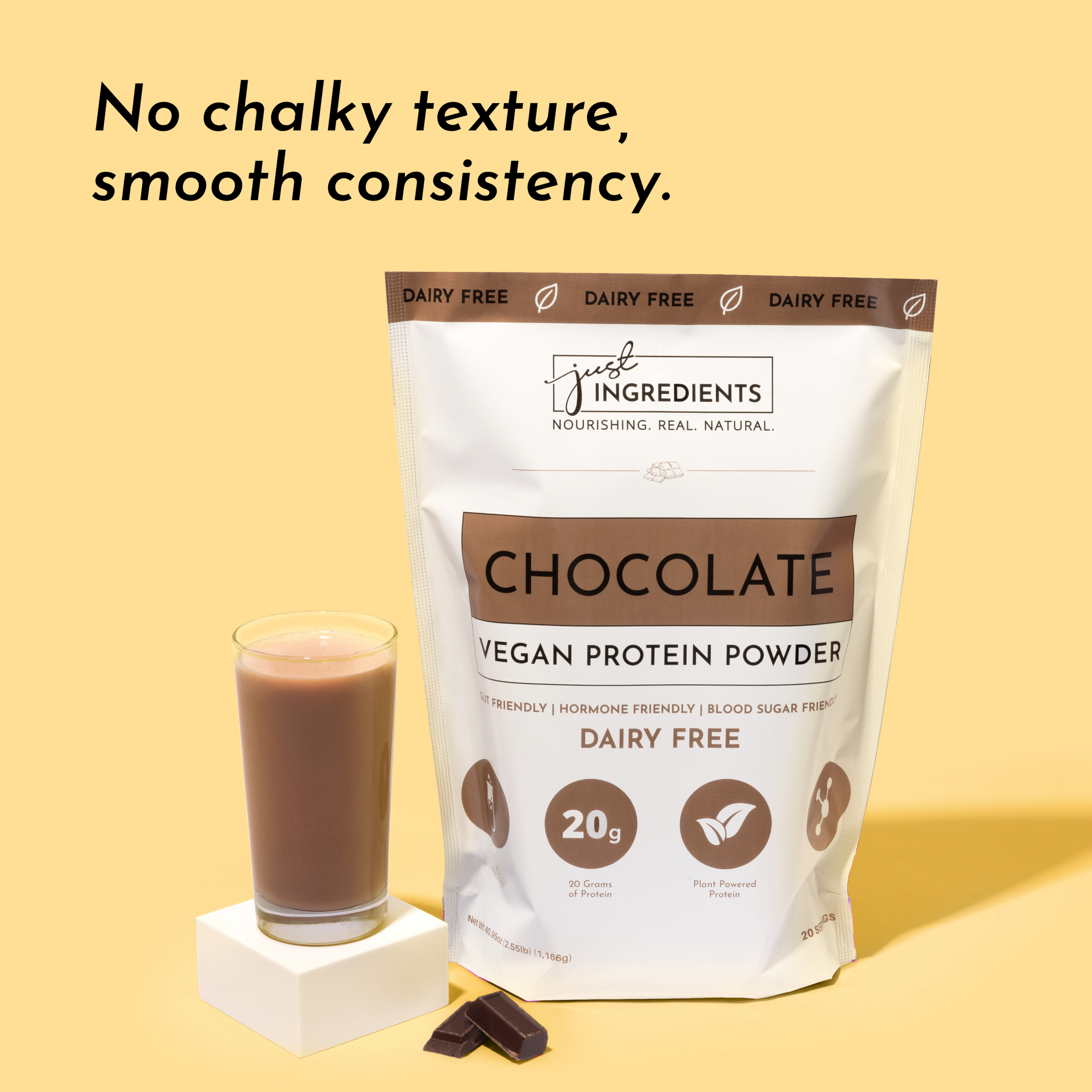 Chocolate vegan protein powder bag next to a glass of chocolate protein shake and a piece of dark chocolate.