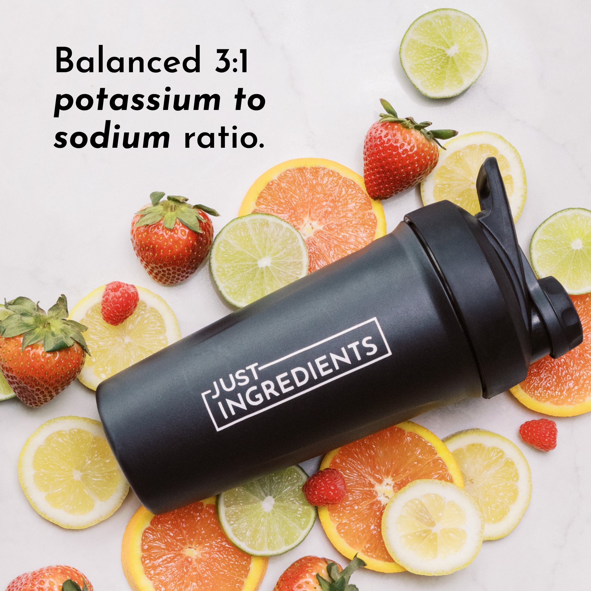 Black shaker bottle with "Just Ingredients" label surrounded by various citrus fruits and strawberries.