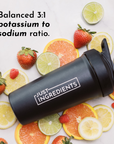 Black shaker bottle with "Just Ingredients" label surrounded by various citrus fruits and strawberries.