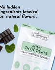 Mint chocolate protein powder package with chocolate pieces and mint leaves on a light background.