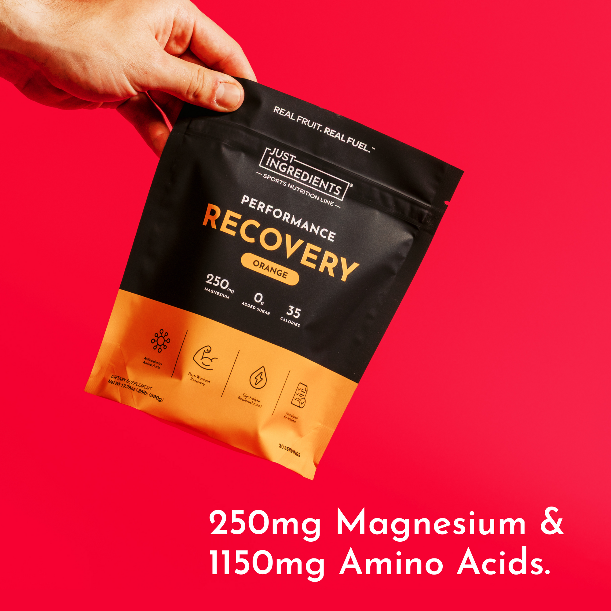 Hand holding black and orange pouch of orange-flavored performance recovery drink against red background.