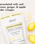 Probiotic complex package with yellow design, featuring lemons and ginger on a marble surface.