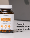 Brown glass bottle with white cap containing orange capsules labeled "Whole Food Vitamin C Complex Supplement" by Just Ingred