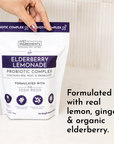 Pouch of Elderberry Lemonade Probiotic Complex with a hand holding it, featuring details about ingredients and servings.