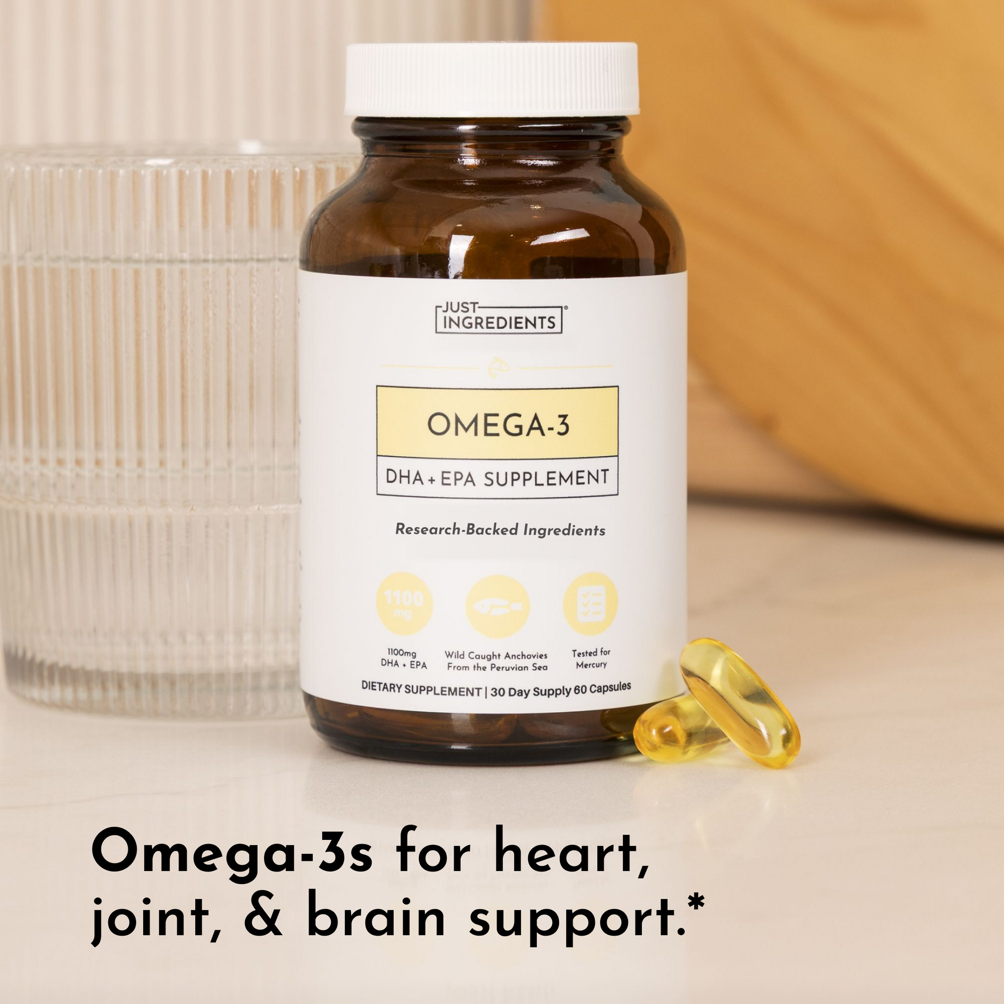 Brown glass bottle with white cap labeled "Omega-3 DHA + EPA Supplement" by Just Ingredients, with two yellow gel capsules be