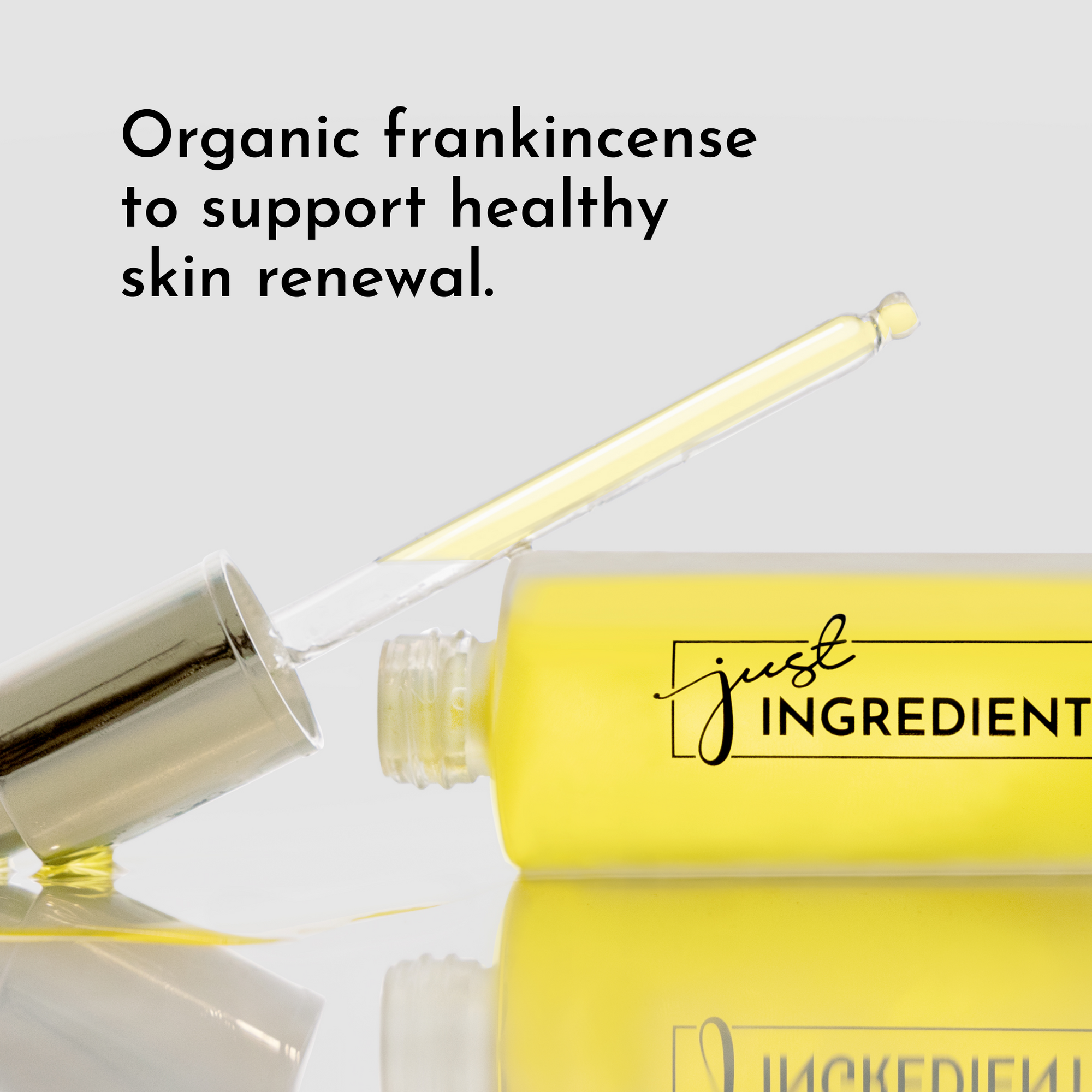 Yellow face serum bottle with dropper, labeled "just INGREDIENTS," on a reflective surface.