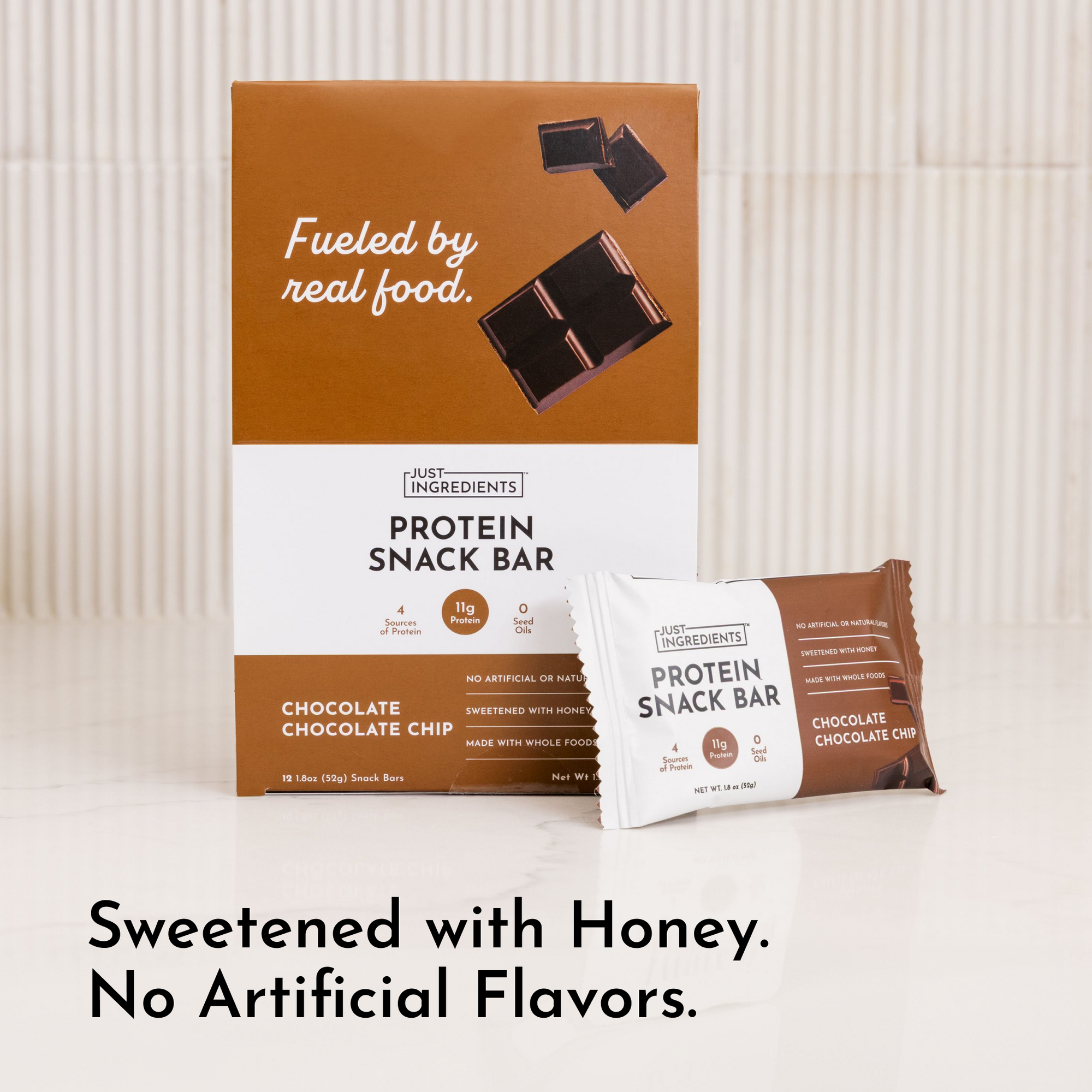 Box of protein snack bars with one individual bar displayed, featuring chocolate chocolate chip flavor and honey sweetening.