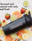 Black shaker bottle with "JUST INGREDIENTS" label surrounded by fresh strawberries, oranges, lemons, and limes.