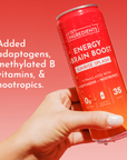 Hand holding a red can of "Energy Brain Boost" with a gradient background, featuring text about its ingredients.