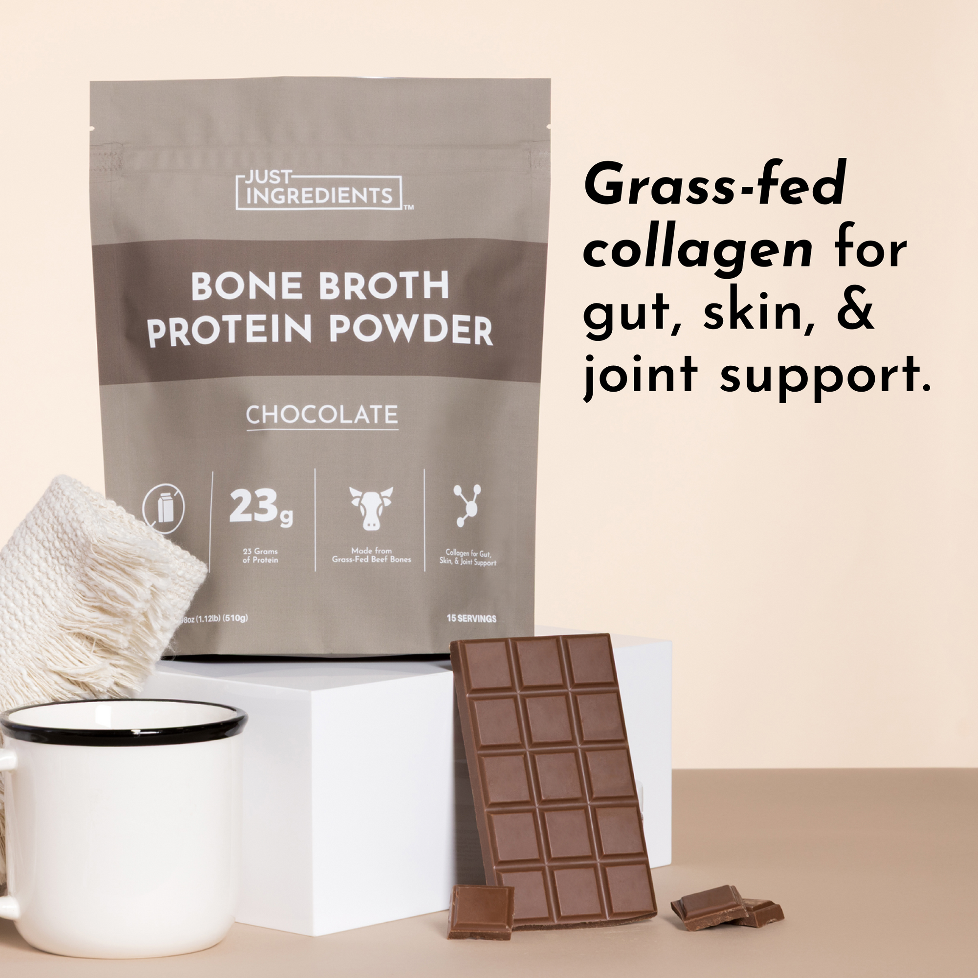Bag of Just Ingredients bone broth protein powder with a chocolate bar and candle on a beige background