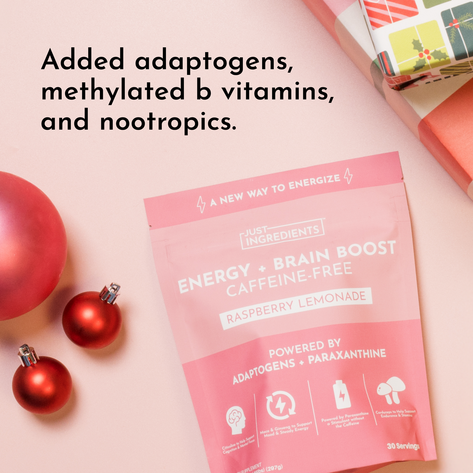 Pink pouch of "Energy + Brain Boost" raspberry lemonade supplement with decorative ornaments and gift wrapping in the backgro
