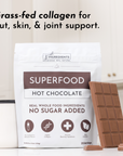 Packaging of Superfood Hot Chocolate with a chocolate bar and a white mug in a kitchen setting.