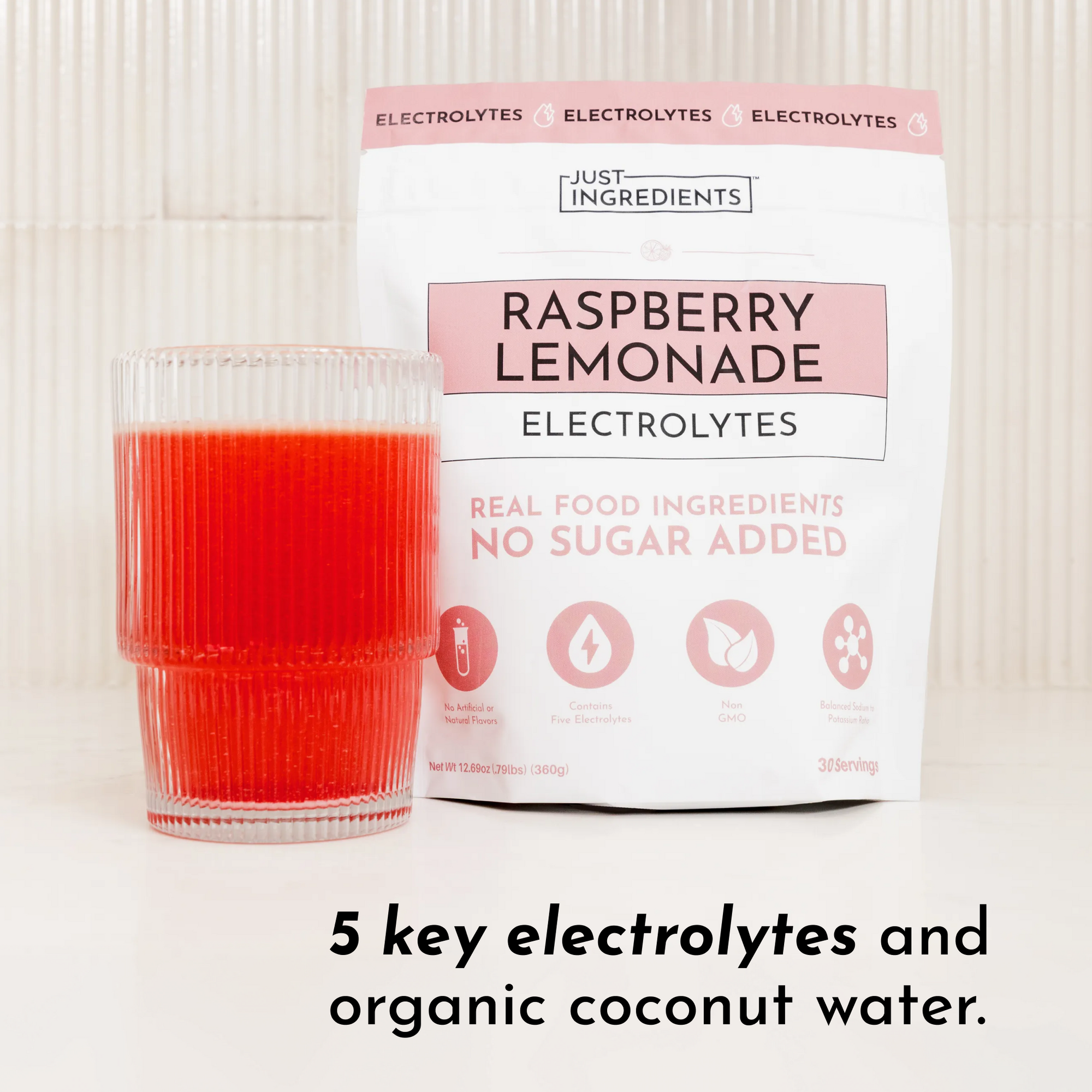 A glass of red raspberry lemonade next to a bag labeled "Raspberry Lemonade Electrolytes" with nutritional information.