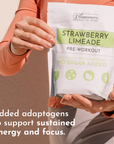 Hand holding a pouch of Strawberry Limeade Pre-Workout with the nutrition panel visible.
