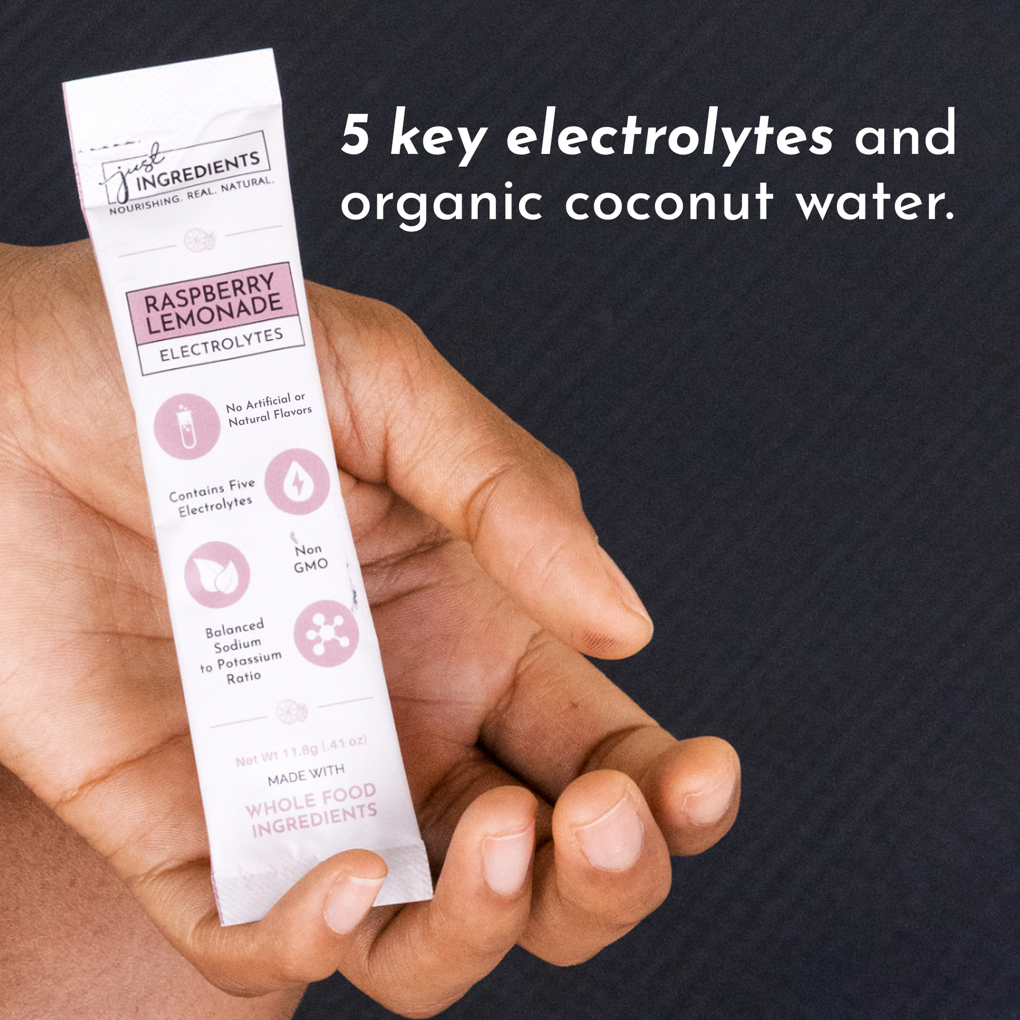 A hand holds a stick packet labeled "Raspberry Lemonade Electrolytes" with nutritional information and benefits.