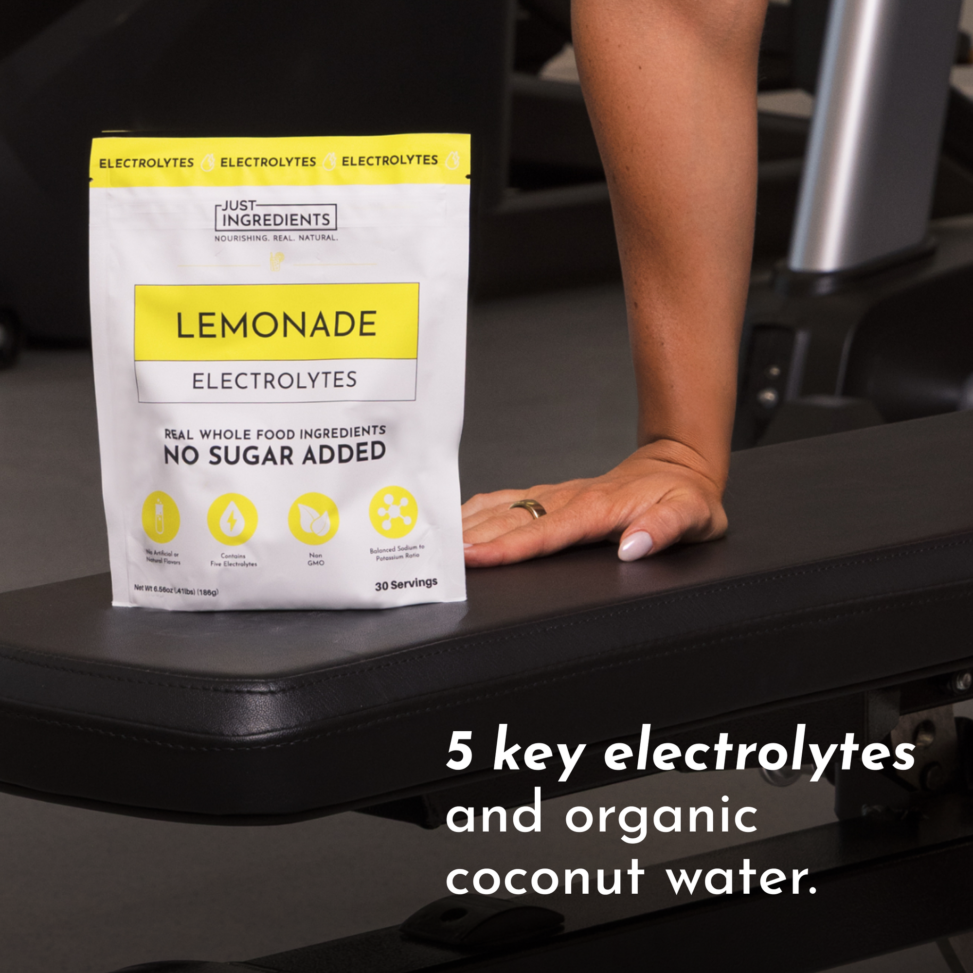 Lemonade Electrolytes package on a gym bench with a hand resting on it, featuring product details and serving information.