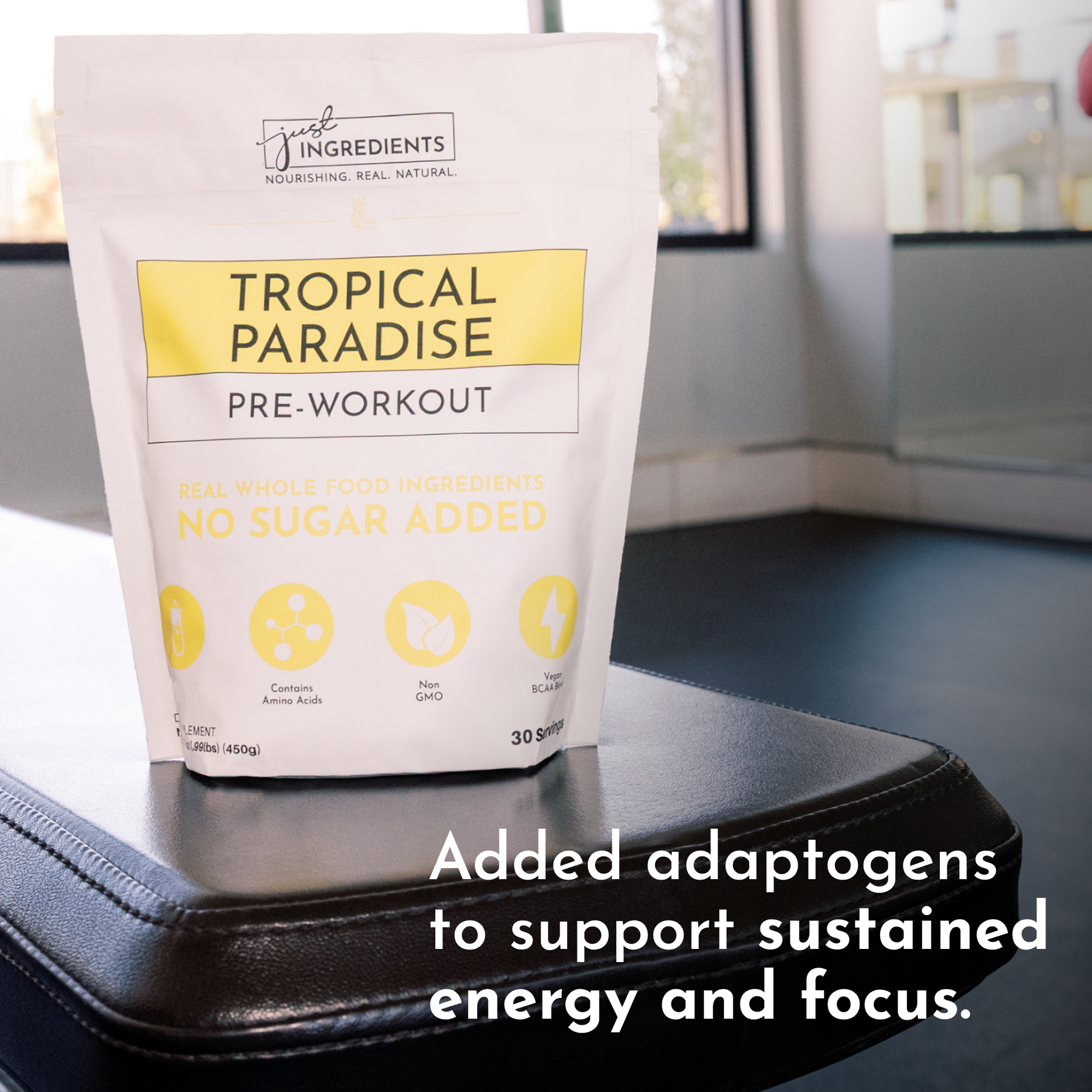 White pouch of "Tropical Paradise Pre-Workout" on a black surface, featuring yellow text and icons.