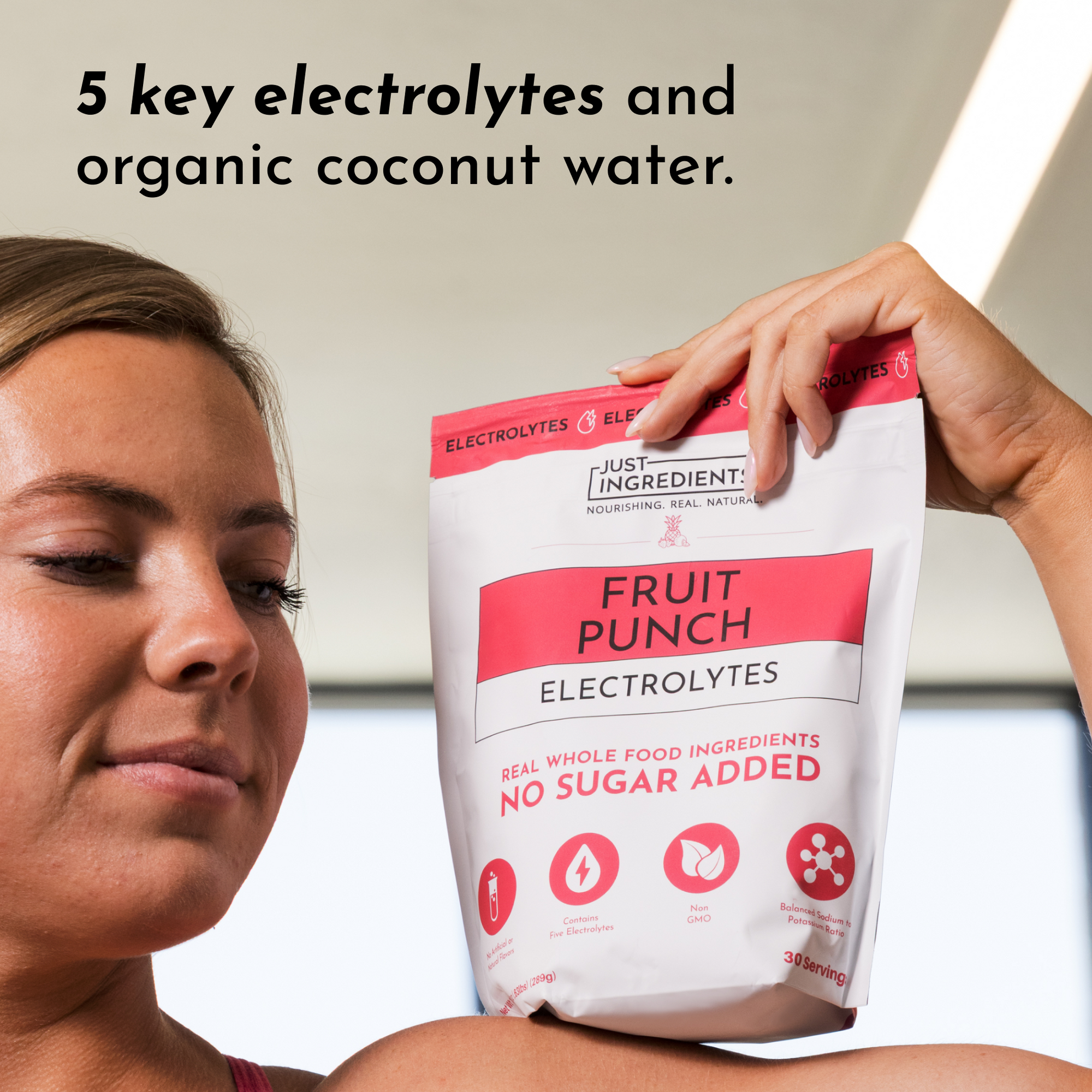 A person holds a bag of Fruit Punch Electrolytes featuring a red and white design with text about its ingredients.