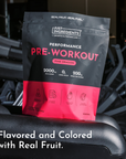 Black and pink pouch of Pink Dragon pre-workout powder with ingredient icons displayed on gym equipment.