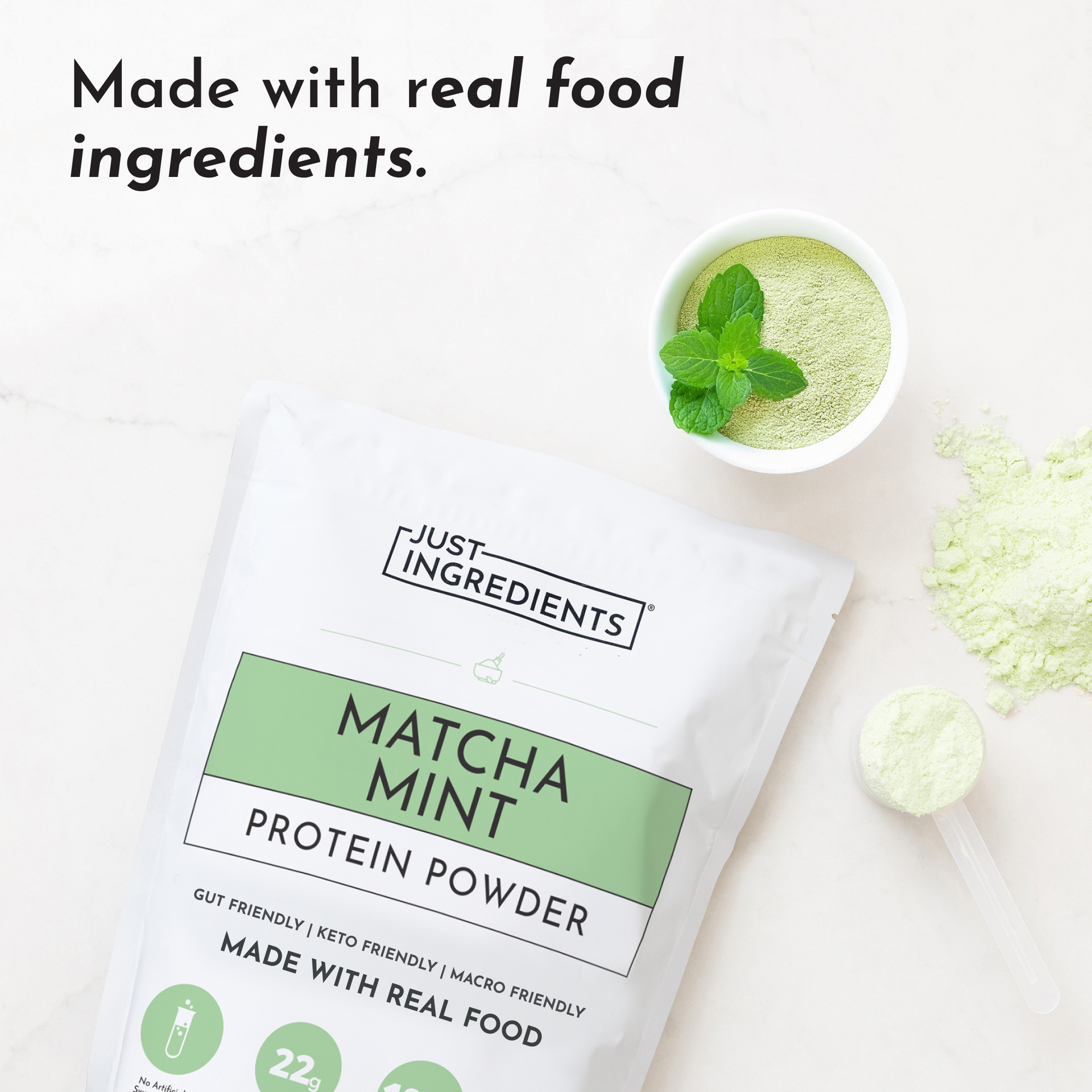 White pouch of matcha mint protein powder with green label, surrounded by green powder and a bowl of mixed powder topped with