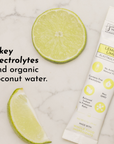 Lime slices and a stick pack of lemon lime electrolytes on a marble surface.